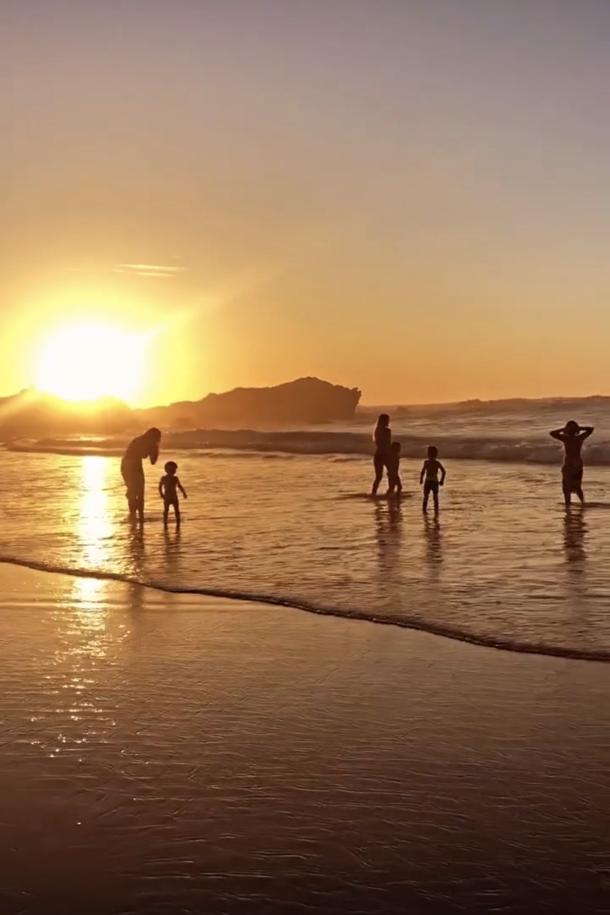 Kinder im flachen Wasser bei Sonnenuntergang